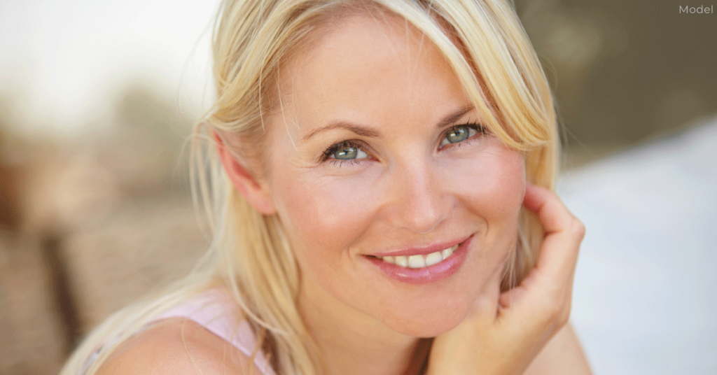 Woman smiling while placing a hand on her cheek