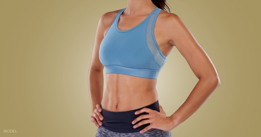woman in sports gear with toned abs with her hands on her hips (model)