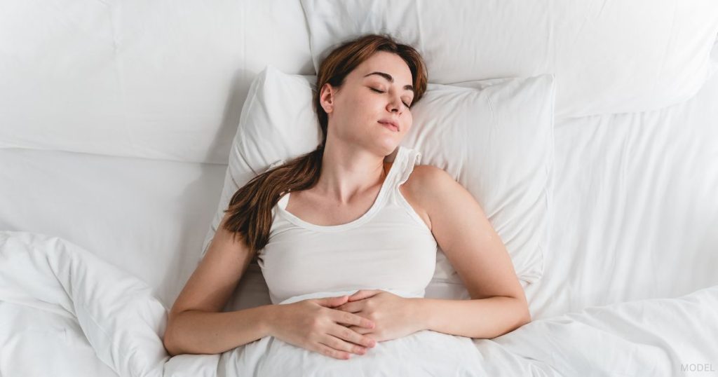 A woman sleeping in bed on their back. (Model)