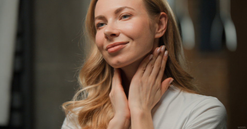 Woman touching her neck with both hands, smiling (model)